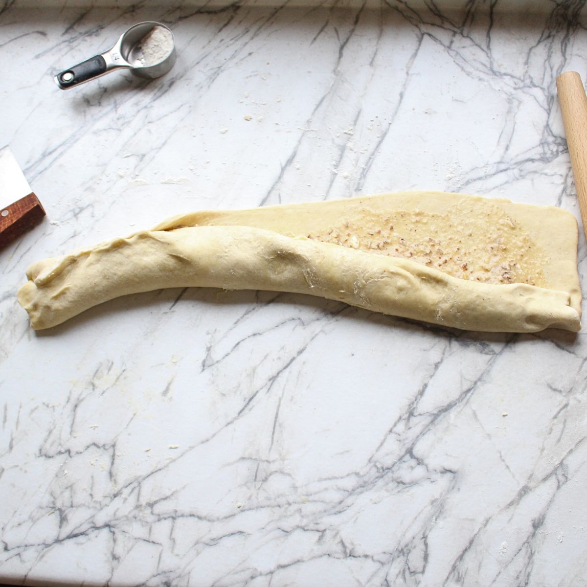 Swedish cardamom coffee cake dough rolled up with filling showing on the right hand side.