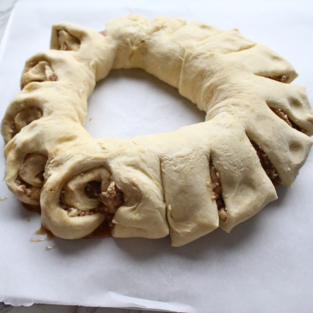Swedish cardamom coffee cake in the process of cutting the pieces around the ring and turning them.