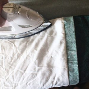 A close up of ironing the contrasting band and trim away from the pillowcase body after it has been sewn together.