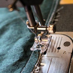 The contrasting band, trim and pillowcase body being zigzagged stitched at the edge of the seam on the sewing machine.