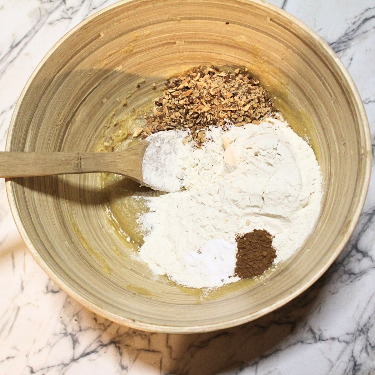 A wooden bowl with dry ingredients and chopped nuts in it for Almond Icebox cookie dough.