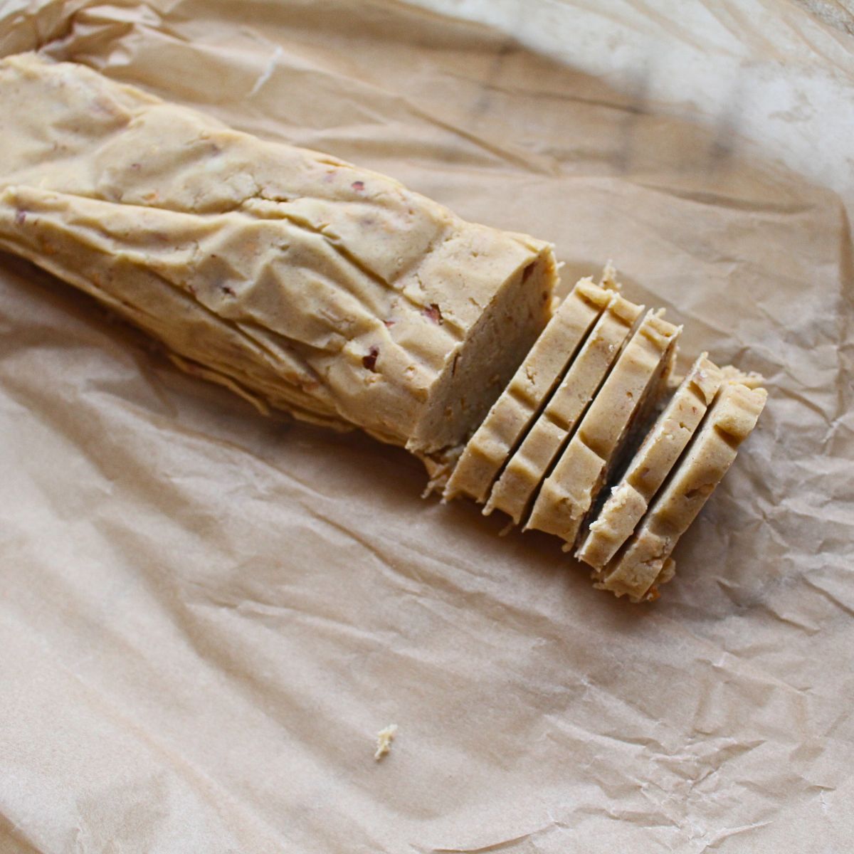 A log of Almond Icebox cookie dough being cut into pieces.