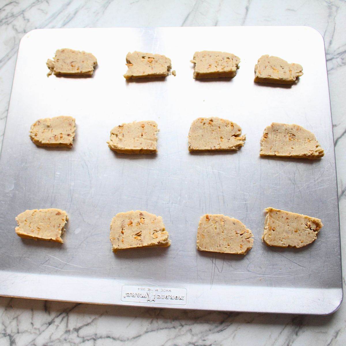 Almond Icebox cookie dough laid out on a cookie sheet for baking.