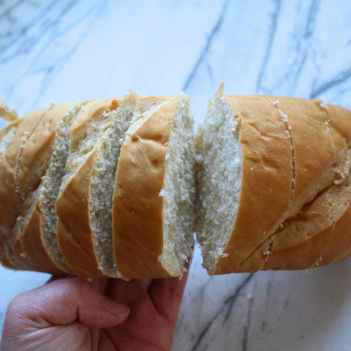 A loaf of french bread sliced, but showing the bread was not cut all the way through for garlic bread.