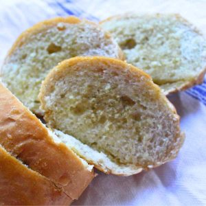 A close up of homemade garlic bread loaf with three slices off the loaf to show the middle.