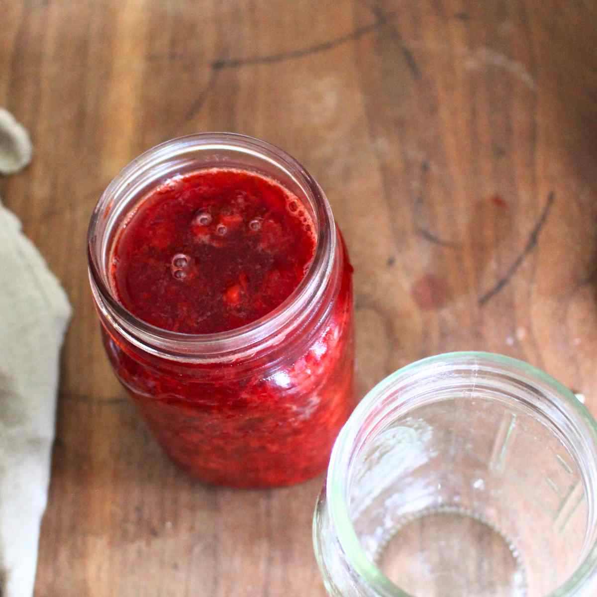 A jar of strawberry sauce viewed from the top after it has been filled without the lid or ring on it yet.
