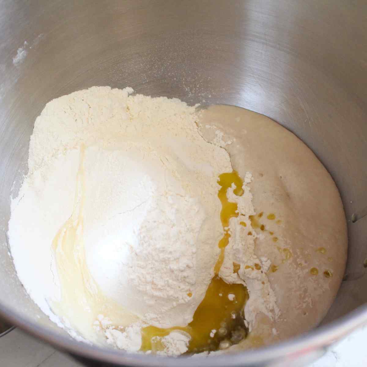 A mixer bowl with flour and other ingredients for 1 hour dinner rolls.