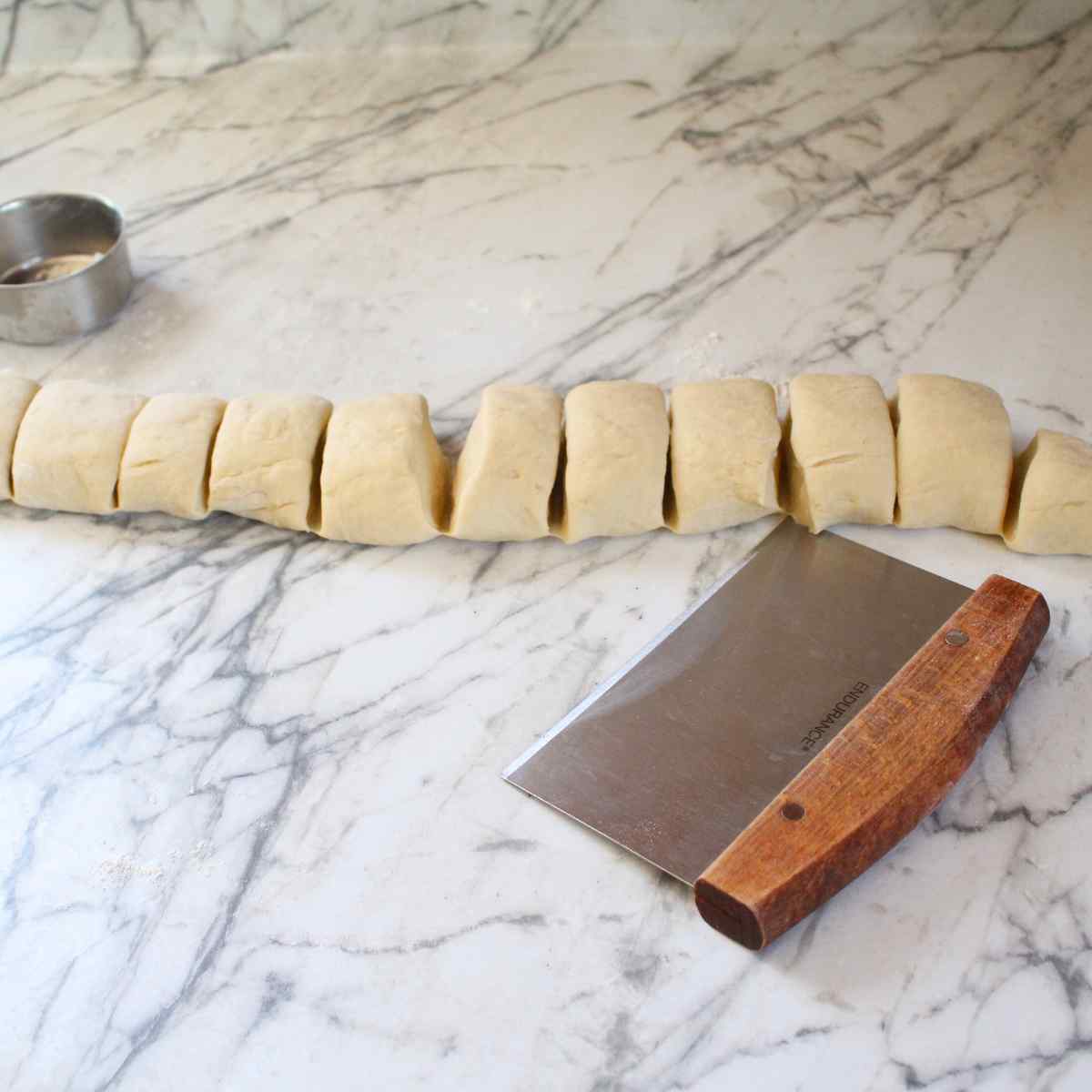A rope of dough cut into pieces for dinner rolls.
