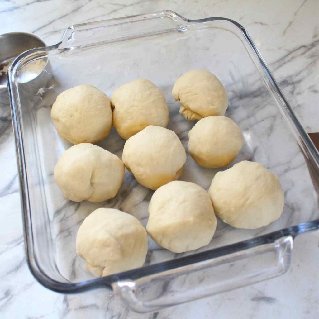 Shaped dinner rolls in a glass baking dish.
