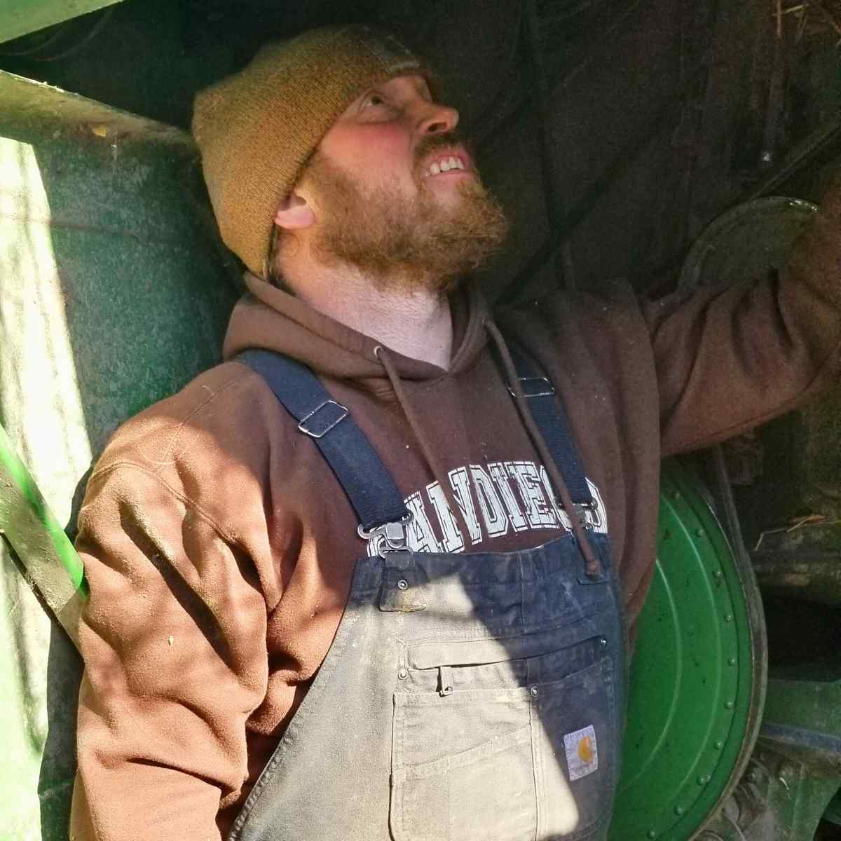 A man fixing a combine in winter clothing.