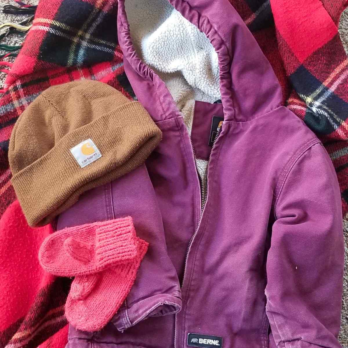A child's purple winter jacket with a brown Carhartt had on the left, and below it a pair of mittens.