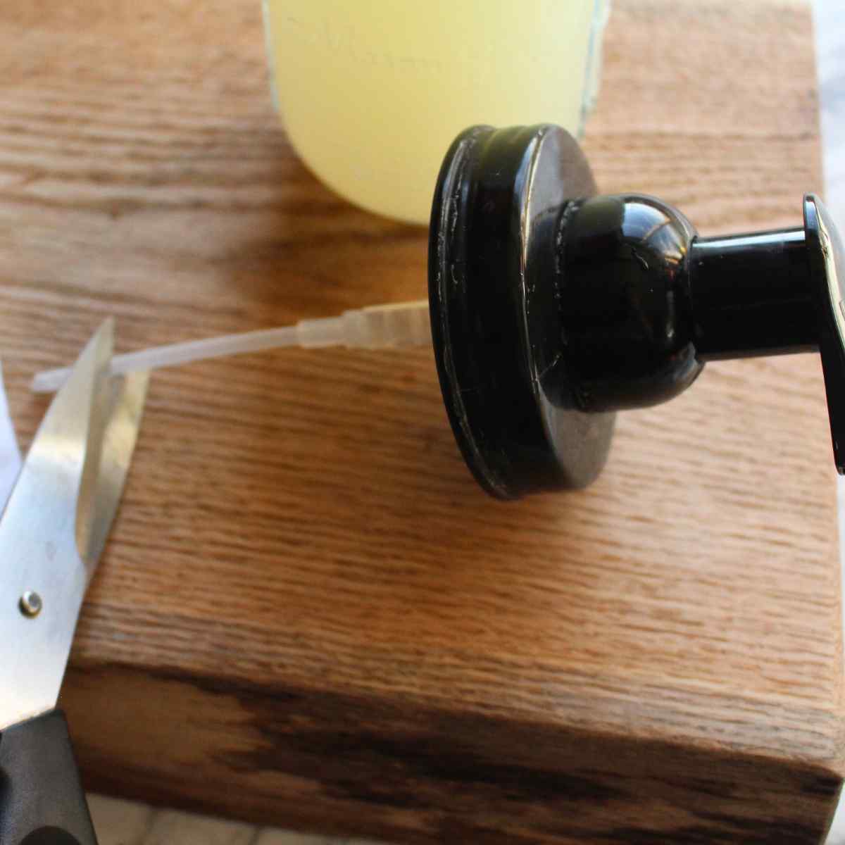 A scissors cutting the foaming hand soap dispenser straw for DIY foaming hand soap.