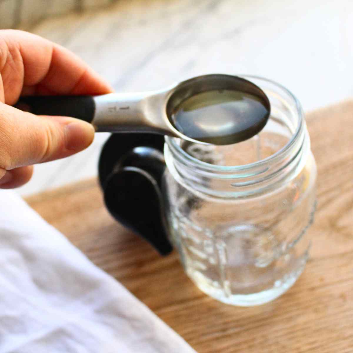 Pouring in a tablespoon of Castile soap into a foaming hand soap bottle.