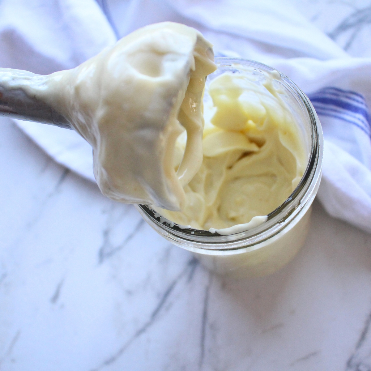 An immersion blender above a glass jar with homemade miracle whip on it.