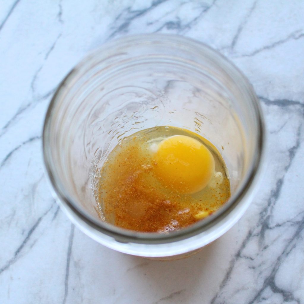 An egg with spices and vinegar in a glass jar.
