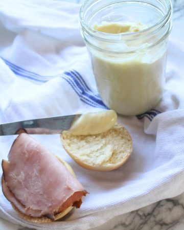 Homemade miracle whip being spread with a knife on sandwich bread.